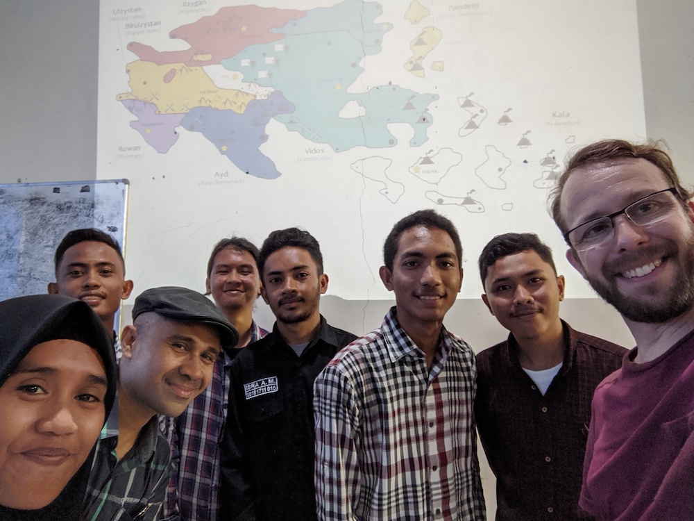 Lev, Halik, and Indonesian students smiling in front of a digital map of an Asia-type fictional continent