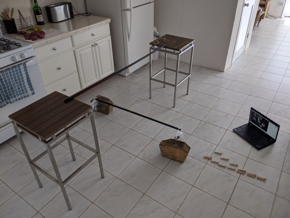 A version of the Cavendish experiment using bar stools, curtain rods, string, baggies, and rocks