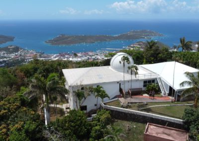 A small observatory building, with a dome housing a telescope, overlooking the Caribbean city of Charlotte Amalie and the deep blue Caribbean Sea