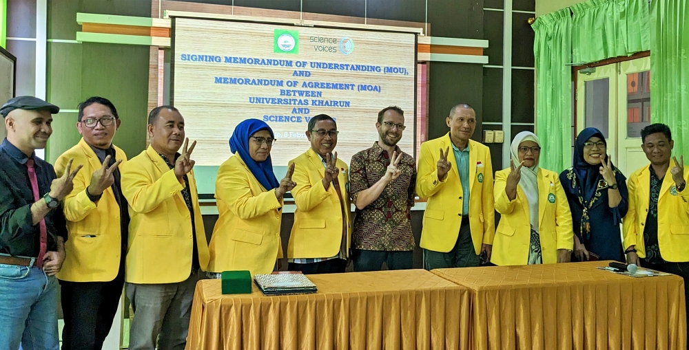 Ten people standing in a row, with Indonesians wearing yellow coats