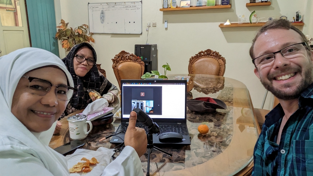 Two women in hijabs (Lily and Mar) on the left of a laptop logged into Zoom, with Lev to the right