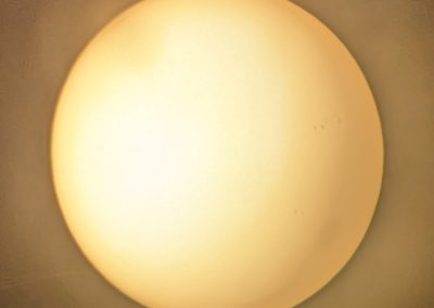 Filtered view of the Sun with a large sunspot in the lower right and a large cluster of sunspots to the upper right of the large sunspot