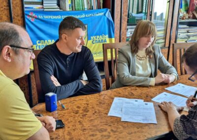 Three men and a woman gathered around a table signing paperwork